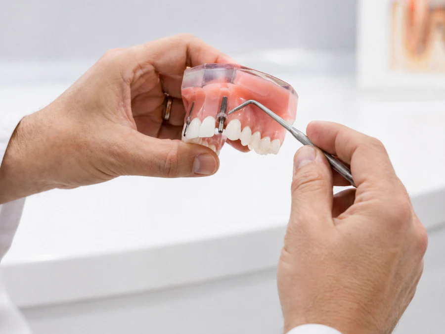 A dentist showing how an implant and crown fit, using a model